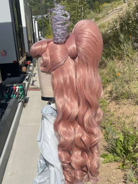 A pink wig with bumper bangs and a Barbiestyle ponytail sit on a mannequin head outside a makeup trailer on the set of...